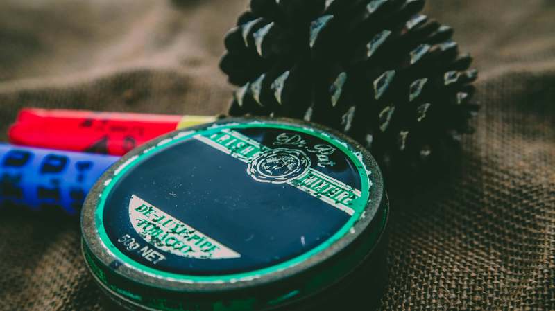 Close-up of three artisanal hair pomades—matte clay, high-shine wax, and water-based cream—arranged diagonally on a marble surface with a vintage comb and textured hair sample